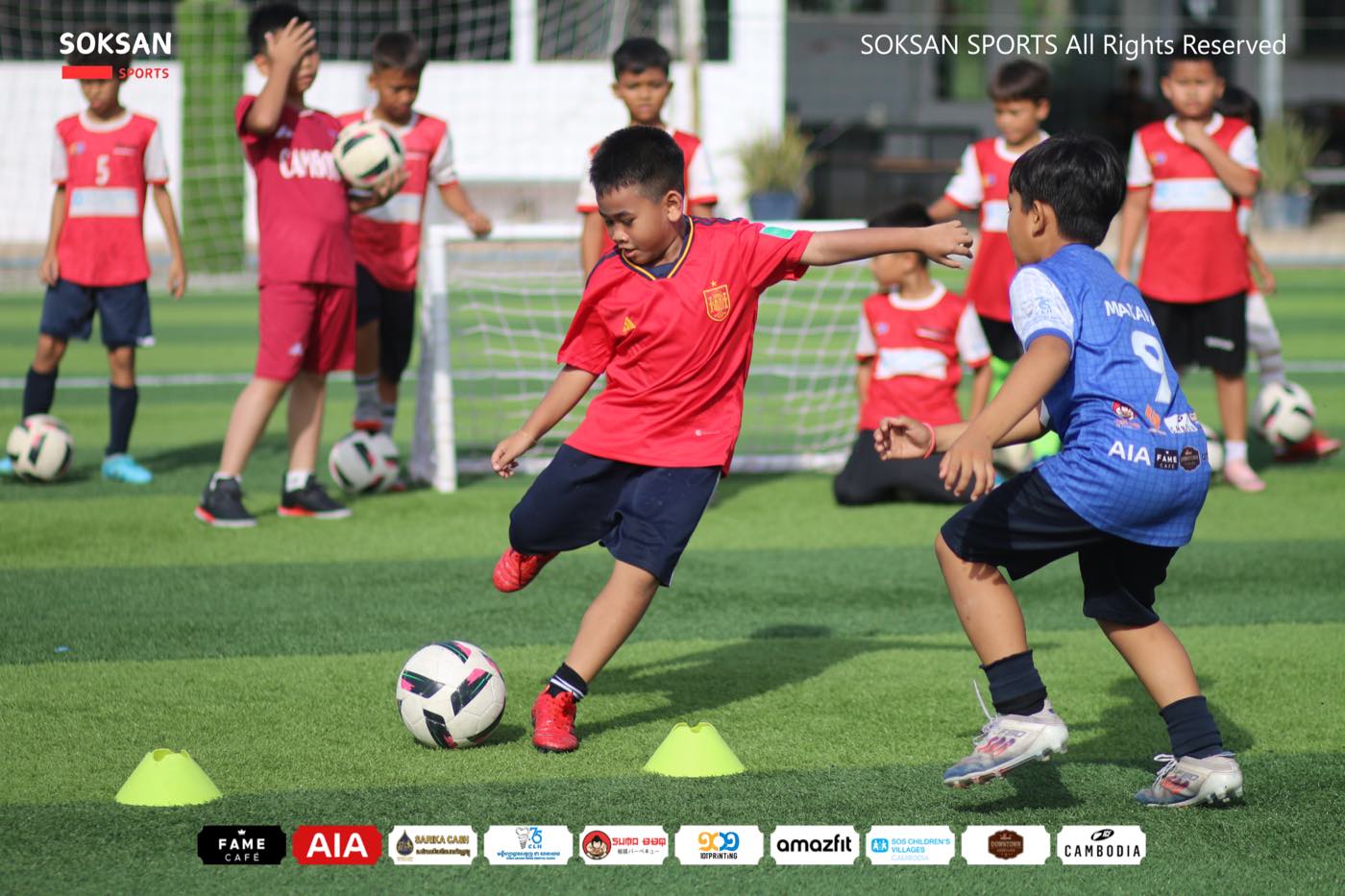 A young player striking the ball during a cones drill as a defender closes in