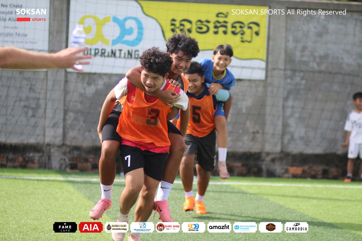 Players in orange bibs laughing and carrying each other after a session
